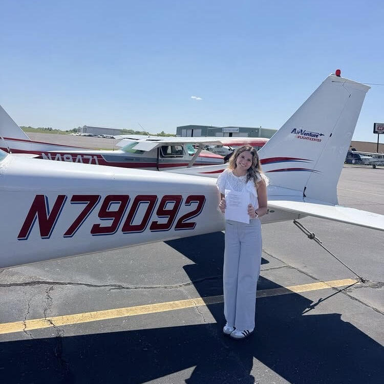 Hailey stands in front of the AirVenture Flight Center C172 with her CFI certificate in hand.
