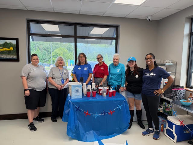 Seven members of the Memphis Chapter stand behind an educational outreach table