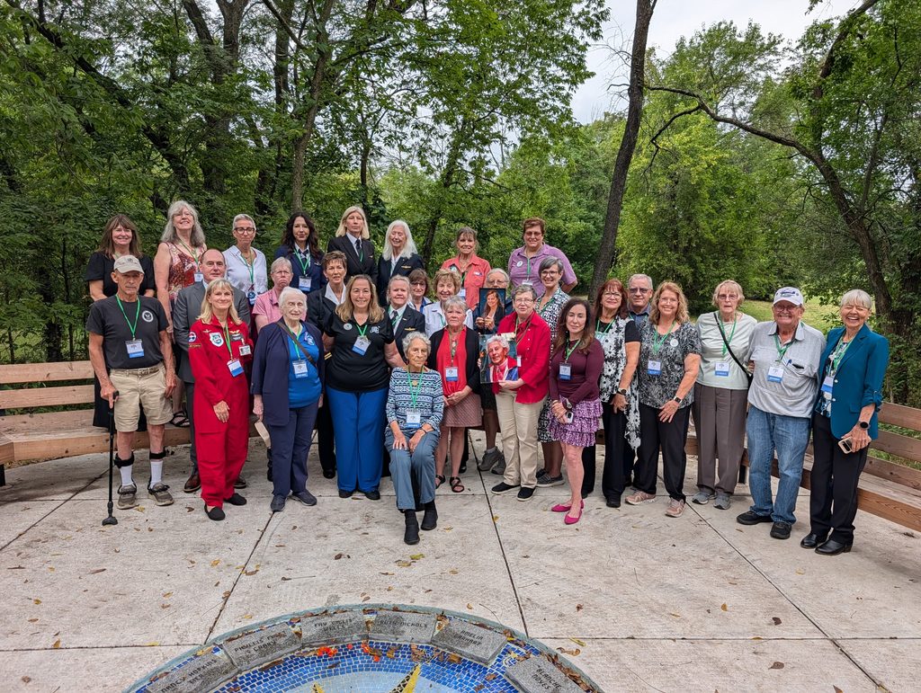 Attendees of the Forest of Friendship Celebration line up outside for a photo around a central logo floor inlay