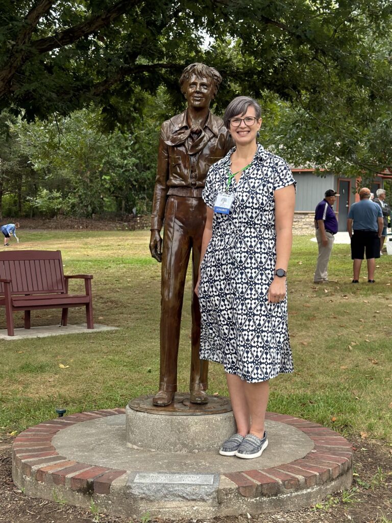 Mandi Hill stands in front of the Amelia Earhart bronze statue outside in the Forest of Friendship.