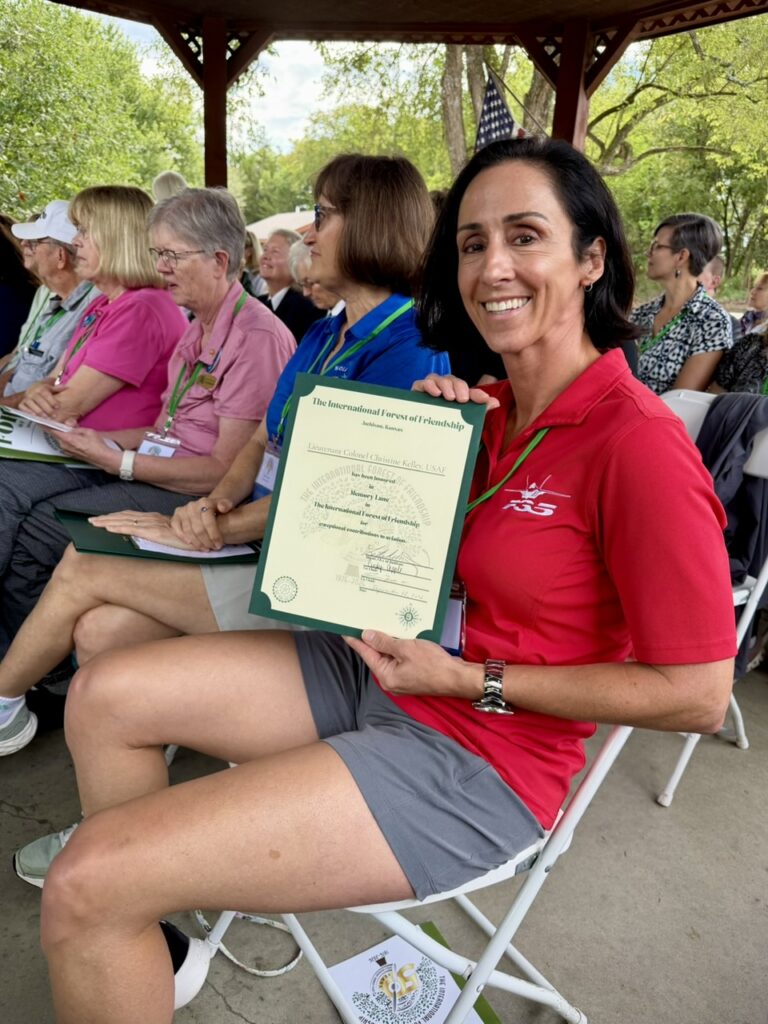 Christine Kelley shows off her Forest of Friendship certificate during the Forest of Friendship outdoor ceremony.